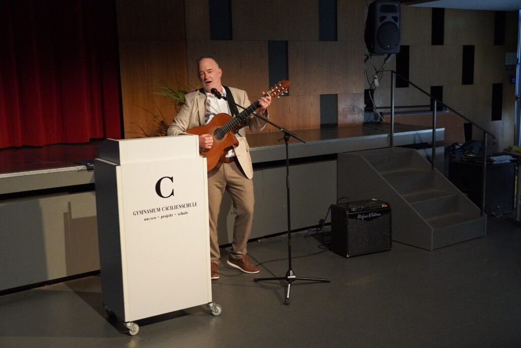 Tutor Heise bei seiner Rede, die er mit einem Lied mit seiner Gitarre begleitet