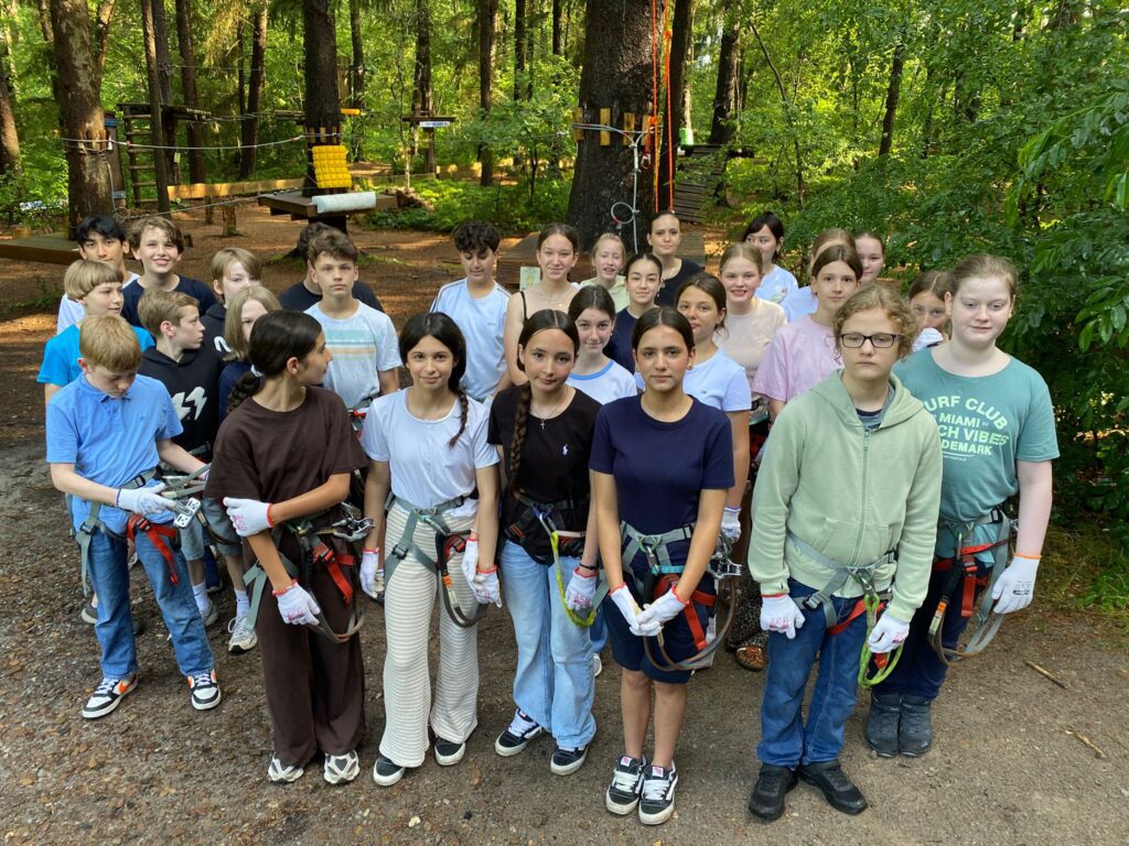 Klassenfoto in Kletterausrüstung im Wald