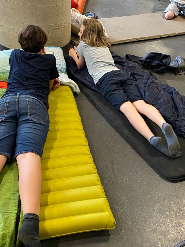Schüler liegen auf Matratzen und unterhalten sich.