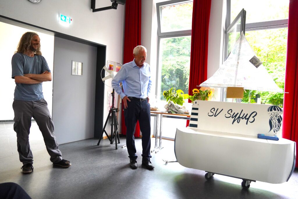 Dr. Syfuß bekommt ein eigenes kleines "Segelboot" überreicht.