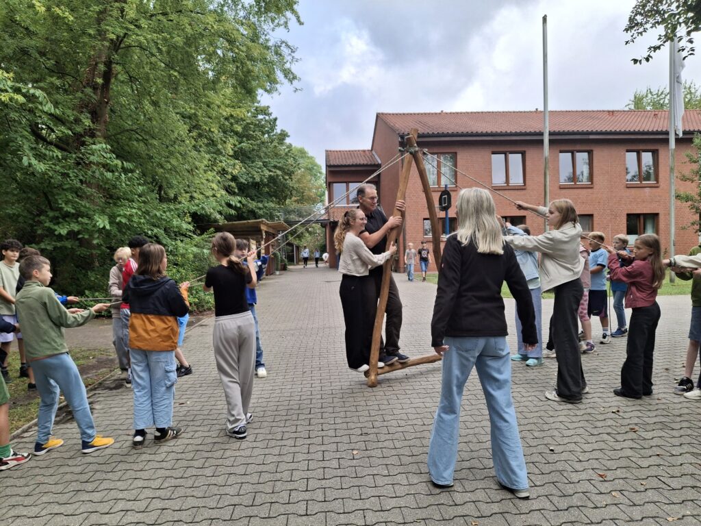 EIne Schülergruppe versucht, durch Zusammenarbeit eine Art von Brücke vorwärts zu bewegen.