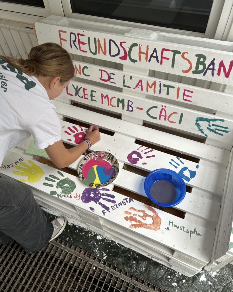 Ein Mädchen bemalt eine Freundschaftsbank